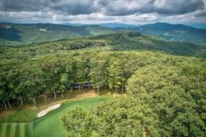 An aerial view of a golf course surrounded by dense forest and mountains. - Love to Beech - Beech Mtn on Golf Course, hot Tub, Pool Table, Club Access Options (Banner Elk)
