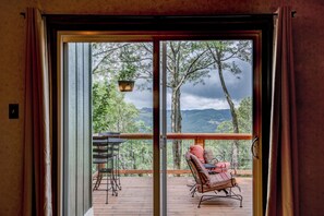 A wooden deck with a chair and table, a sliding glass door, and a view of trees and mountains. - Love to Beech - Beech Mtn on Golf Course, hot Tub, Pool Table, Club Access Options (Banner Elk)