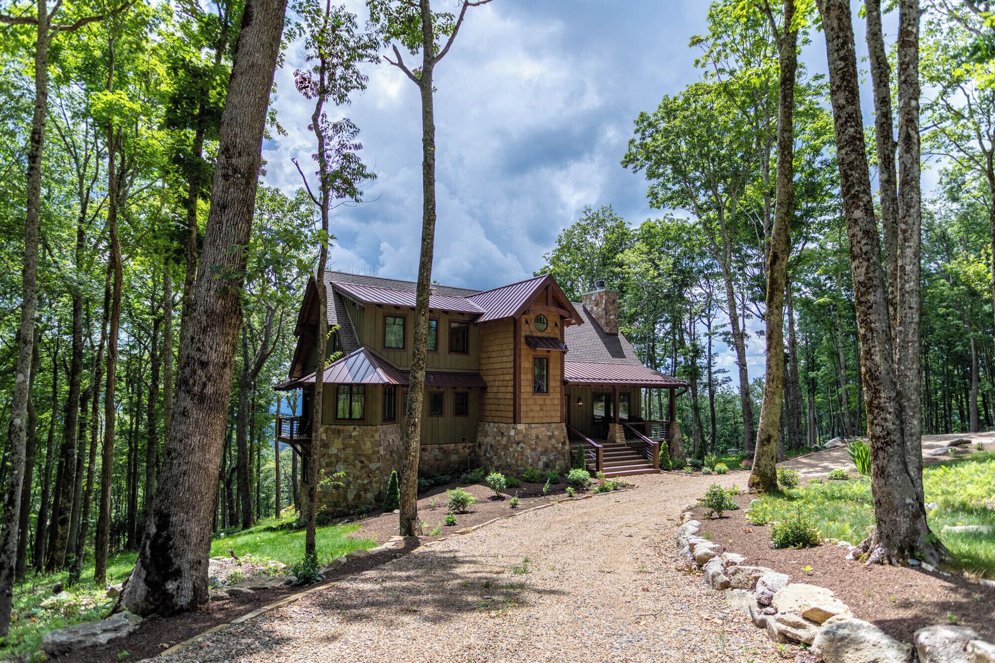 A cabin with a stone foundation, wooden exterior, and a porch with a stone chimney.