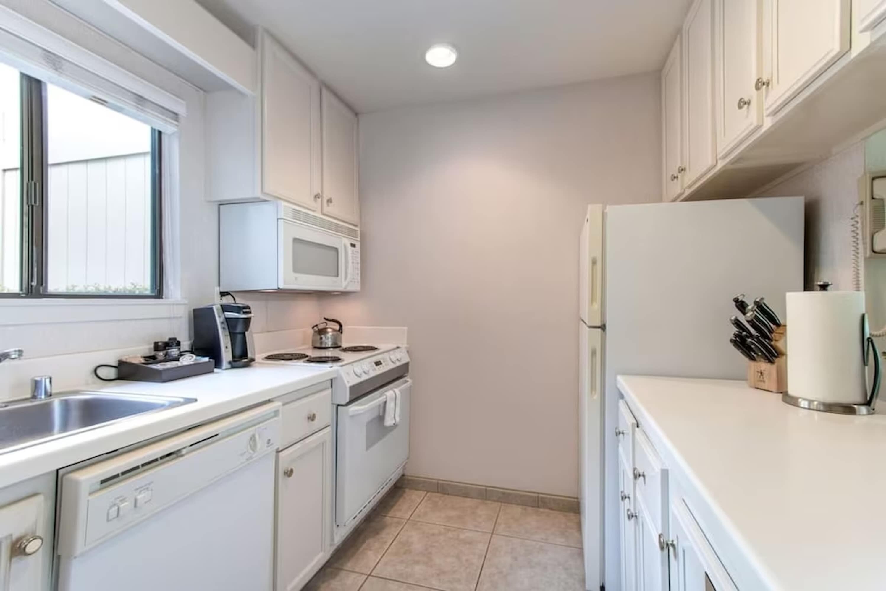 A modern kitchen with white cabinets, a microwave, stove, and refrigerator.