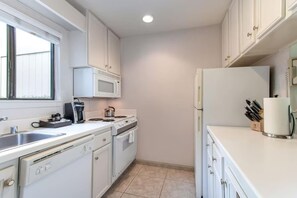 A modern kitchen with white cabinets, a microwave, stove, and refrigerator. - 2BR Napa Getaway Side-by-side Condos Golf View (Napa)