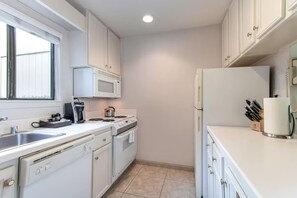 A modern kitchen with white cabinets, a microwave, stove, and refrigerator.