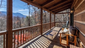 A wooden deck with a bench and chairs, overlooking a forested mountain range. - Mountain Dream (Banner Elk)