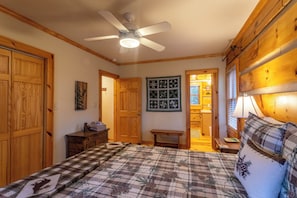 A bedroom with a bed, wooden wardrobe, a ceiling fan, a small table, and a wall with framed pictures. - Mountain Dream (Banner Elk)