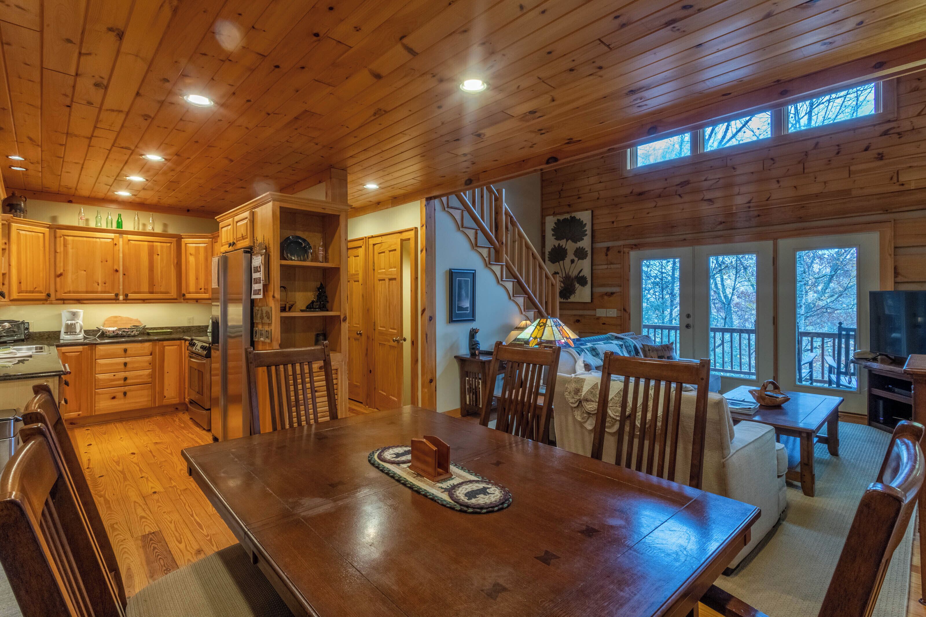 A wooden cabin interior with a dining area, kitchen, and living space.