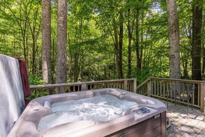 Ein Whirlpool, umgeben von einer Holzterrasse und einem bewaldeten Gebiet.