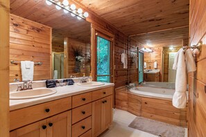 Ein Badezimmer einer Holzhütte mit zwei Waschbecken, einem großen Spiegel und einer Badewanne.