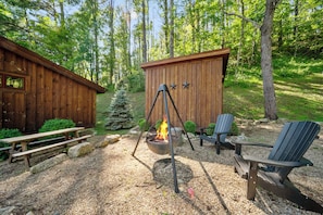 Eine Holzhütte mit Feuerstelle, Picknicktisch und Adirondack-Stühlen.
