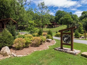 Ein Lodgen Eingang mit einem Schild, umgeben von üppiger Vegetation und einem Steinweg.
