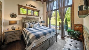A bedroom with a bed, nightstands, a ceiling fan, a window with curtains, and a view of the outdoors. - Red Wolf Chalet at Eagles Nest (Banner Elk)