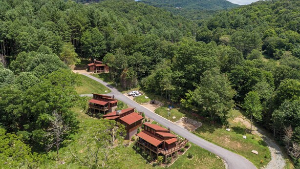 A lodge with multiple cabins surrounded by dense forest, a winding road, and a mountain backdrop. - Red Wolf Chalet at Eagles Nest (Banner Elk)