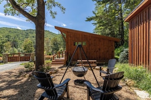 A wooden cabin with a swing chair, a hanging pot, and a view of a forested mountain. - Red Wolf Chalet at Eagles Nest (Banner Elk)