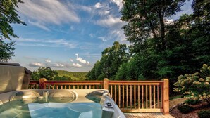 A hot tub on a wooden deck with a view of a forested area.