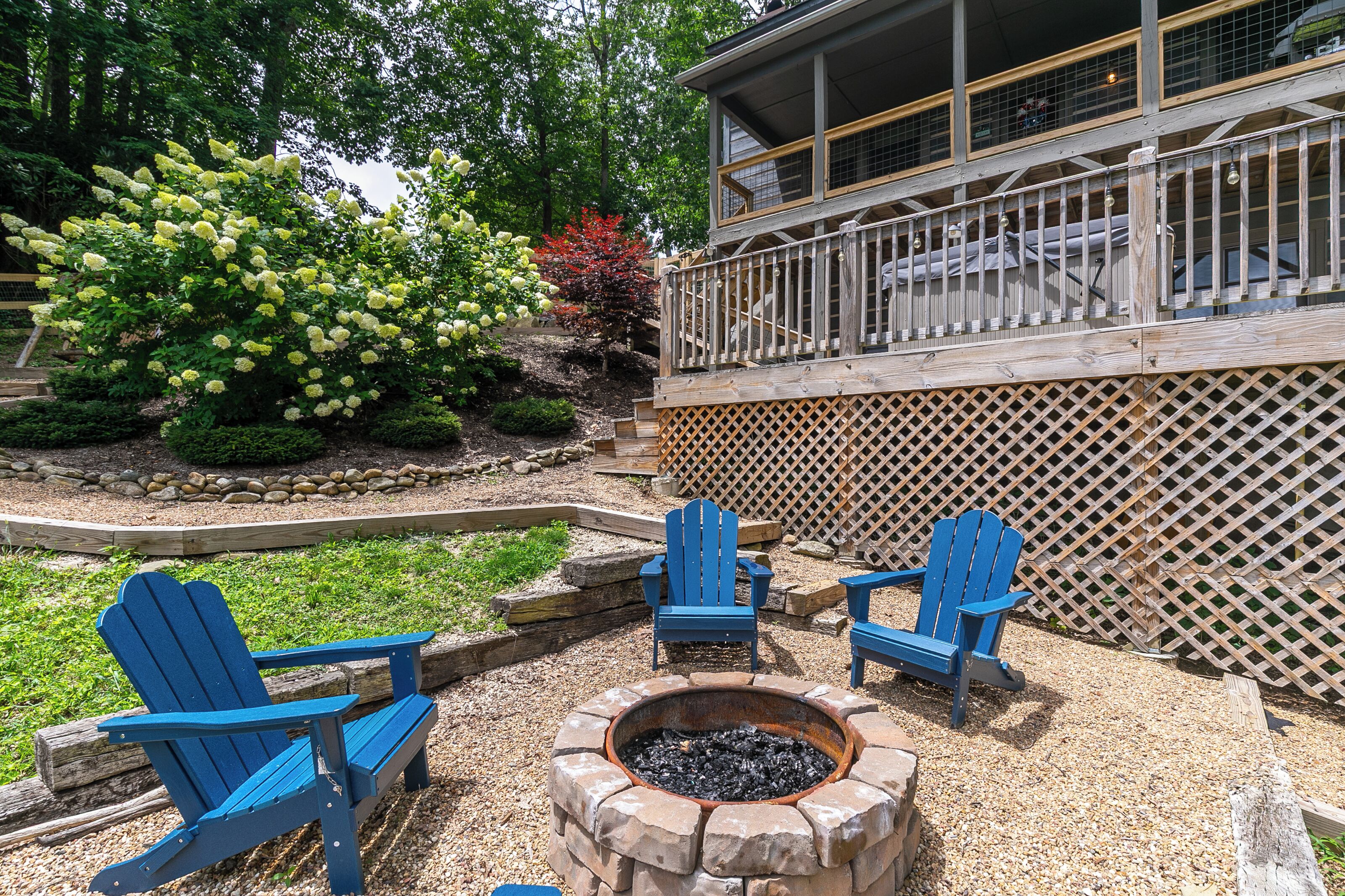 A deck with blue Adirondack chairs, a fire pit, and a wooden fence.
