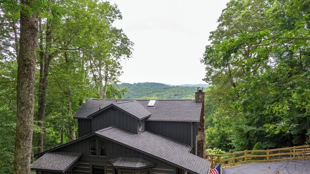 A cabin with a stone chimney, a deck, and an American flag.