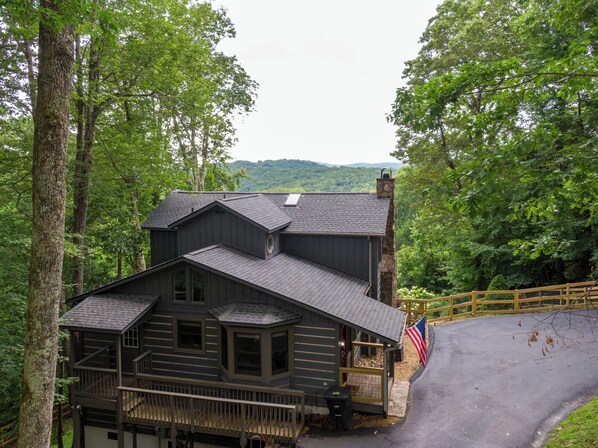 Une cabane avec une cheminée en pierre, une terrasse et un drapeau américain.