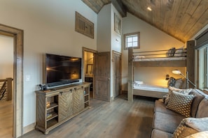 A room with a TV, wooden furniture, a bunk bed, and a window. - Birds Nest Retreat at Eagles Nest (Banner Elk)