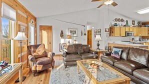 A cozy living room with leather sofas, a glass coffee table, and a ceiling fan. - Sugars Sunset Vista (Banner Elk)