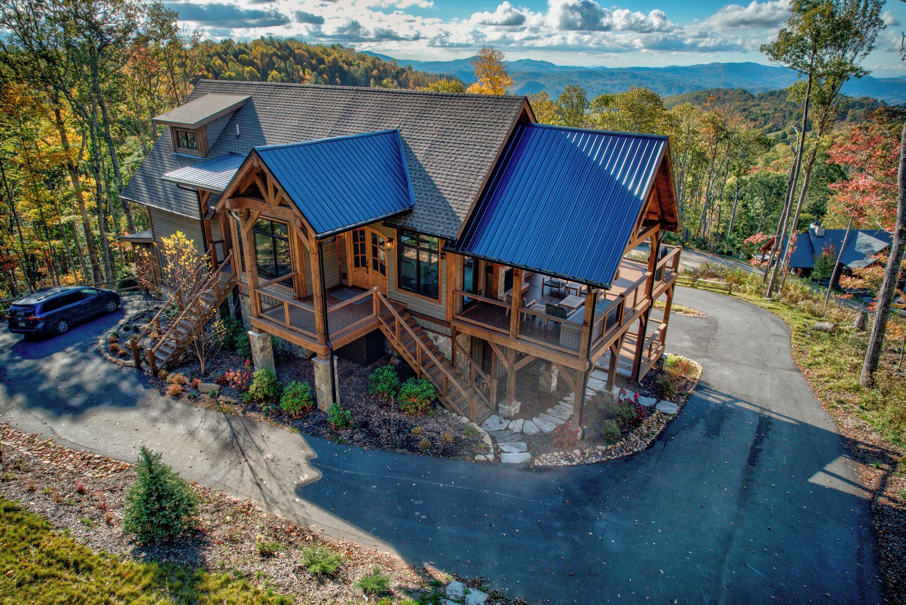 A large wooden cabin with multiple decks and a covered driveway.