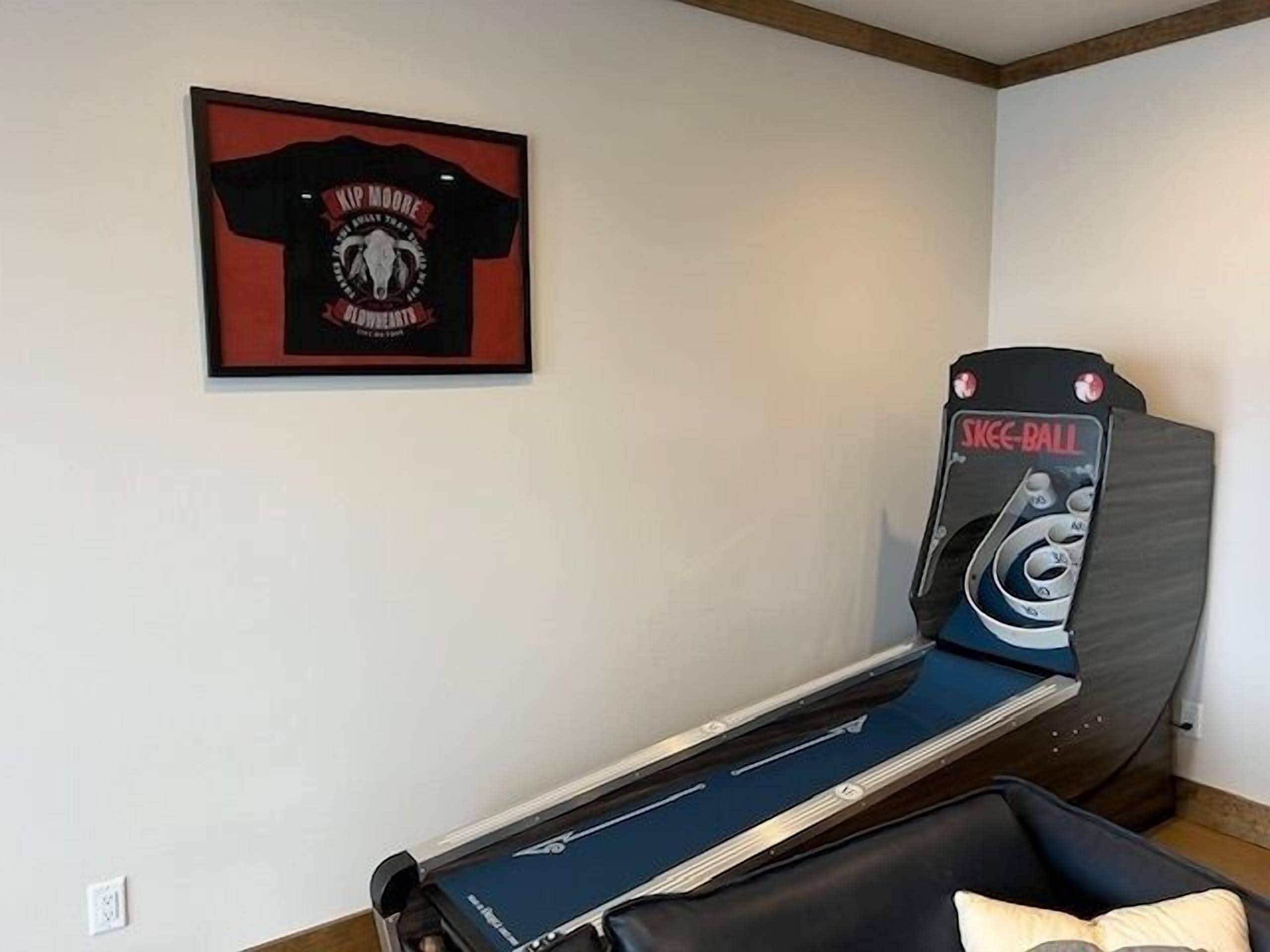 Une table de massage dotée d’un panneau de commande, un t-shirt encadré accroché au mur et un coussin posé sur le sol.