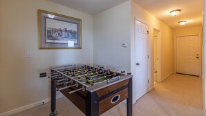 Una stanza con un tavolo da calcio, un quadro appeso al muro e una porta che conduce in un'altra stanza.