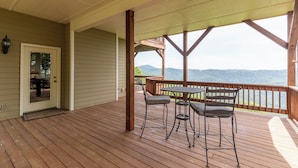 Un patio in legno con zona coperta, una porta e un tavolo con sedie.