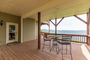 Eine Holzterrasse mit überdachtem Bereich, einer Tür und einem Tisch mit Stühlen.