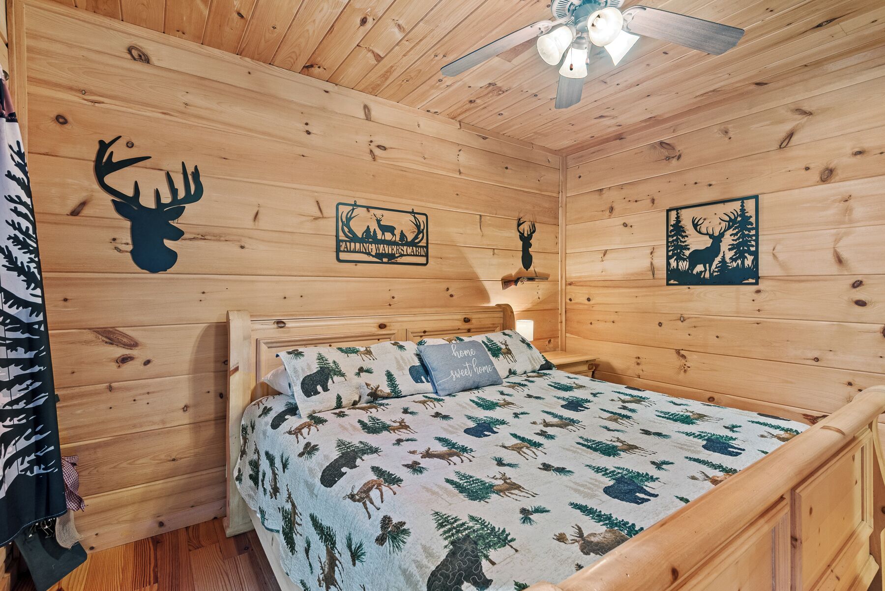 Een houten kamer met een bed, een plafondventilator en decoraties aan de muur, waaronder silhouetten van dieren en een bord.