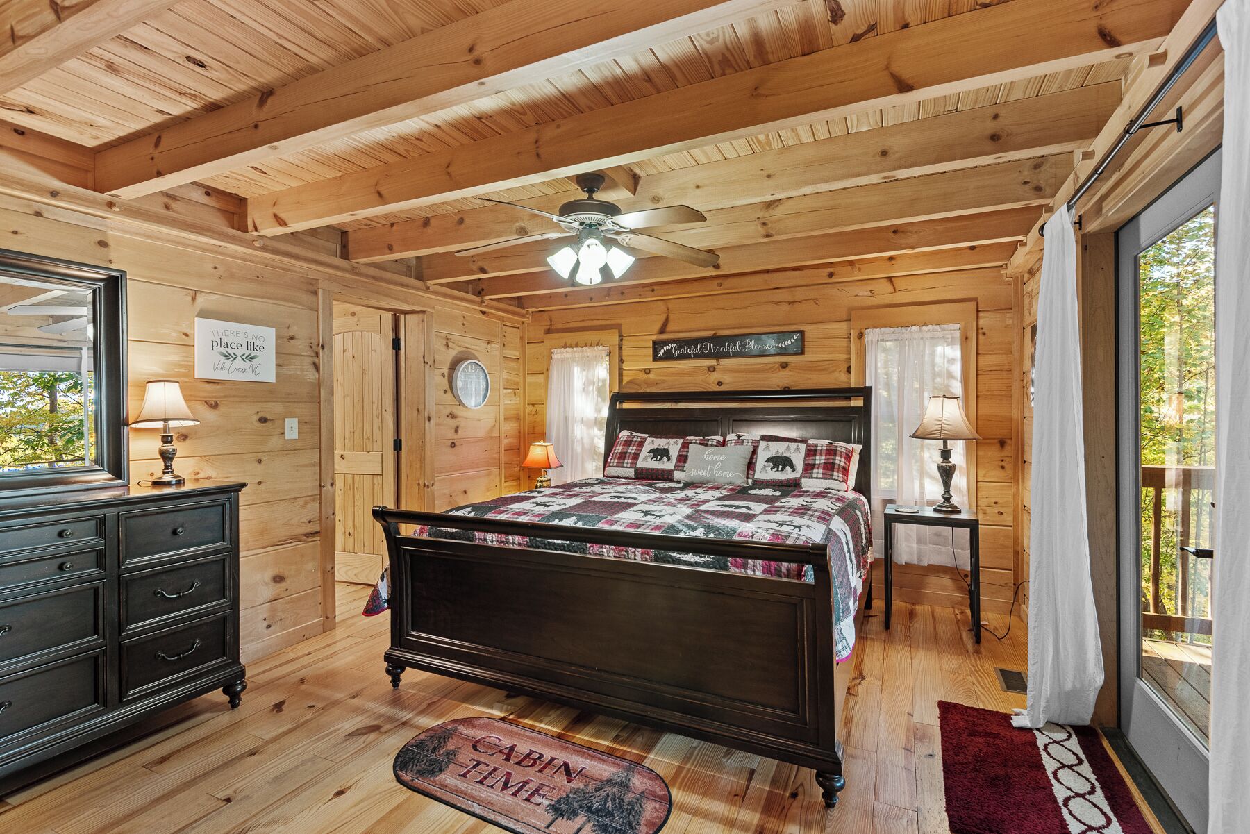 Een slaapkamer in een houten chalet met een bed, een kast en een raam met uitzicht.