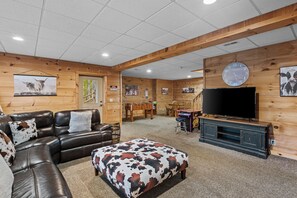 A cozy living room with a leather sofa, ottoman, wooden walls, a flat-screen TV, and a foosball table. - Falling Waters (Banner Elk)