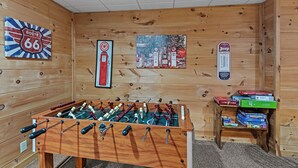 A room with a foosball table, a gas station mural, and a Jeep gas pump sign. - Falling Waters (Banner Elk)