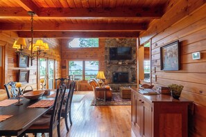 A cozy cabin interior with a dining area, fireplace, and wooden walls. - Mountaintop at Yonahlossee Saddle Club (Boone)