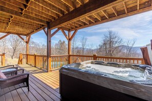 A wooden deck with a hot tub, wicker chairs, and a view of mountains. - Banner Crest - Mountain Luxury! Views, hot Tub, Private Pool and Tennis Courts, Game Room (Banner Elk)