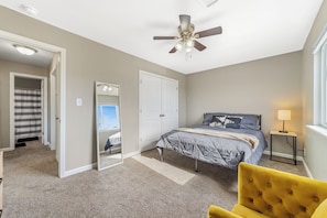 Ein Schlafzimmer mit Bett, Deckenventilator, Spiegel, Tür und Fenster.