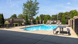 A swimming pool with a picnic table and lounge chairs, surrounded by a brick fence and trees. - Millan Enterprises 311 Hawkins Road (Clarksville)