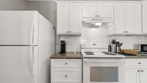 A kitchen with white cabinets, a white refrigerator, a stove, and a microwave. - Millan Enterprises 311 Hawkins Road (Clarksville)