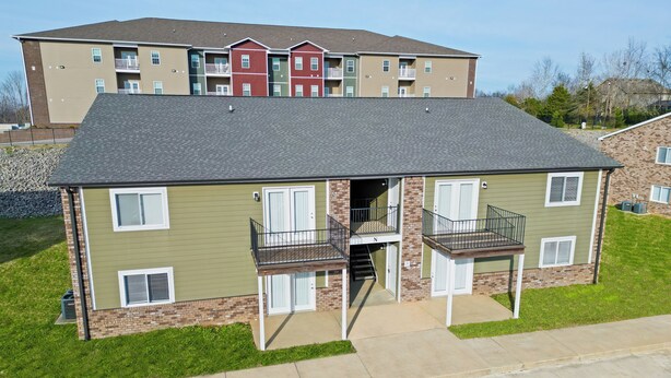A two-story building with a flat roof, a central entrance, and a small balcony on the ground floor. - Millan Enterprises 311 Hawkins Road (Clarksville)