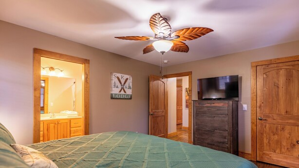 Ein Schlafzimmer mit einem Bett, einem Deckenventilator, einem Fernseher, Holztüren und einem Schild an der Wand.