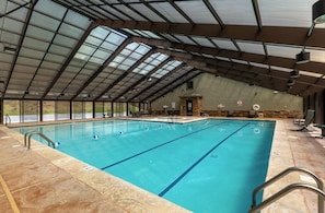Ein Hallenbad mit deutlich abgegrenzten Bahnen, einer Steinwand und einer überdachten Dachkonstruktion.