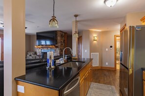 Eine moderne Küche mit Kochinsel, Backofen, Kühlschrank und einer Wand mit Steinverkleidung.