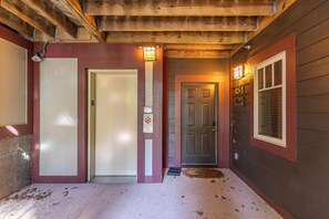 Eine Holzwand mit einer roten Tür, einer weißen Tür und einem Fenster mit Rollläden.