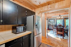 A modern kitchen with dark cabinets, stainless steel appliances, and a wooden ceiling. - Crystal View (Boone)