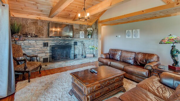 Una sala de estar acogedora con chimenea de piedra, sofá de cuero y una mesa de centro de madera.