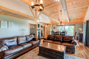 A spacious living room with leather sofas, a wooden coffee table, and a chandelier. - Crystal View (Boone)