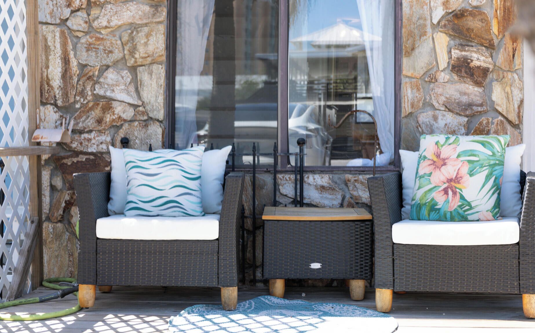 Un espace patio aménagé avec des meubles en osier, des murs en pierre et une porte en verre.