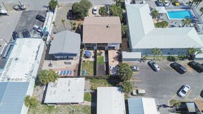 An aerial view of a building with a rooftop patio, a swimming pool, and a parking lot.