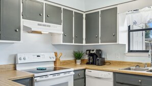 A kitchen with a stove, oven, dishwasher, and a coffee maker.