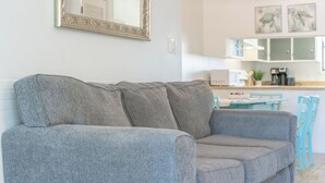A grey sofa in a living area with a kitchen in the background.