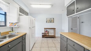 A compact kitchen with a refrigerator, sink, and wooden countertops. - Sea Esta - Minutes to Beach Pet-friendly! (Panama City Beach)