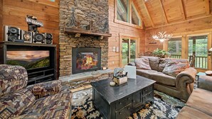 A cozy log cabin interior with a fireplace, comfortable seating, and a television. - Log Heaven (Banner Elk)